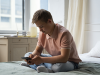 Source: Magnific; Copyright: freepik; URL: https://www.magnific.com/free-photo/side-view-boy-with-down-syndrome-holding-phone_29448932.htm#fromView=search&page=1&position=1&uuid=e5af902c-24dc-434c-8012-5dba627380bb&query=adolescent+male+looking+at+phone+at+home; License: Licensed by JMIR.